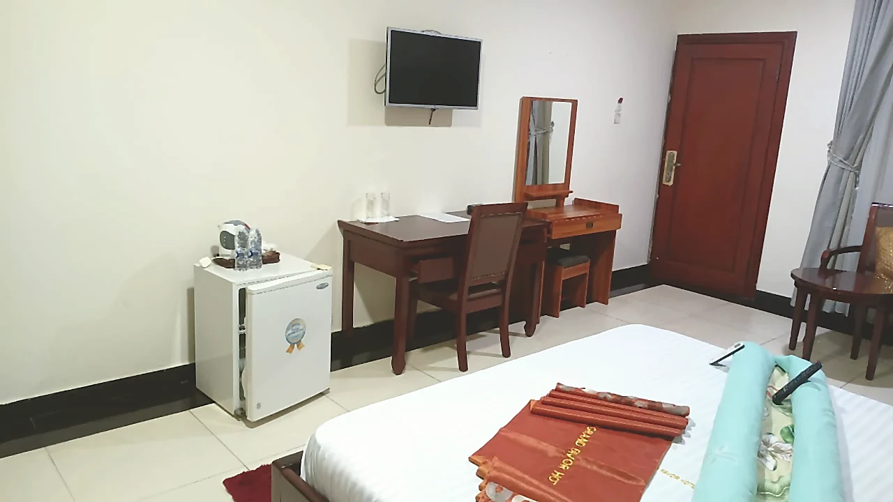 Guest room amenities with desk, mini fridge, and bed at Grand Favor Hotel